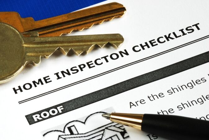 Close up of a home inspection checklist form with a pair of keys and a pen resting on top, lighlighting the section labeled Roof.