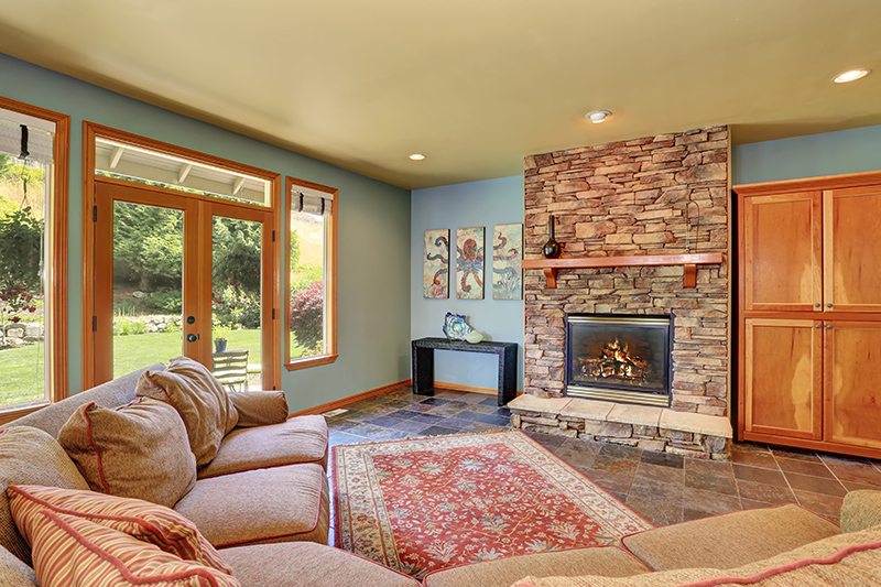 Cozy living room with blue walls, tile floor and stone tile fireplace.