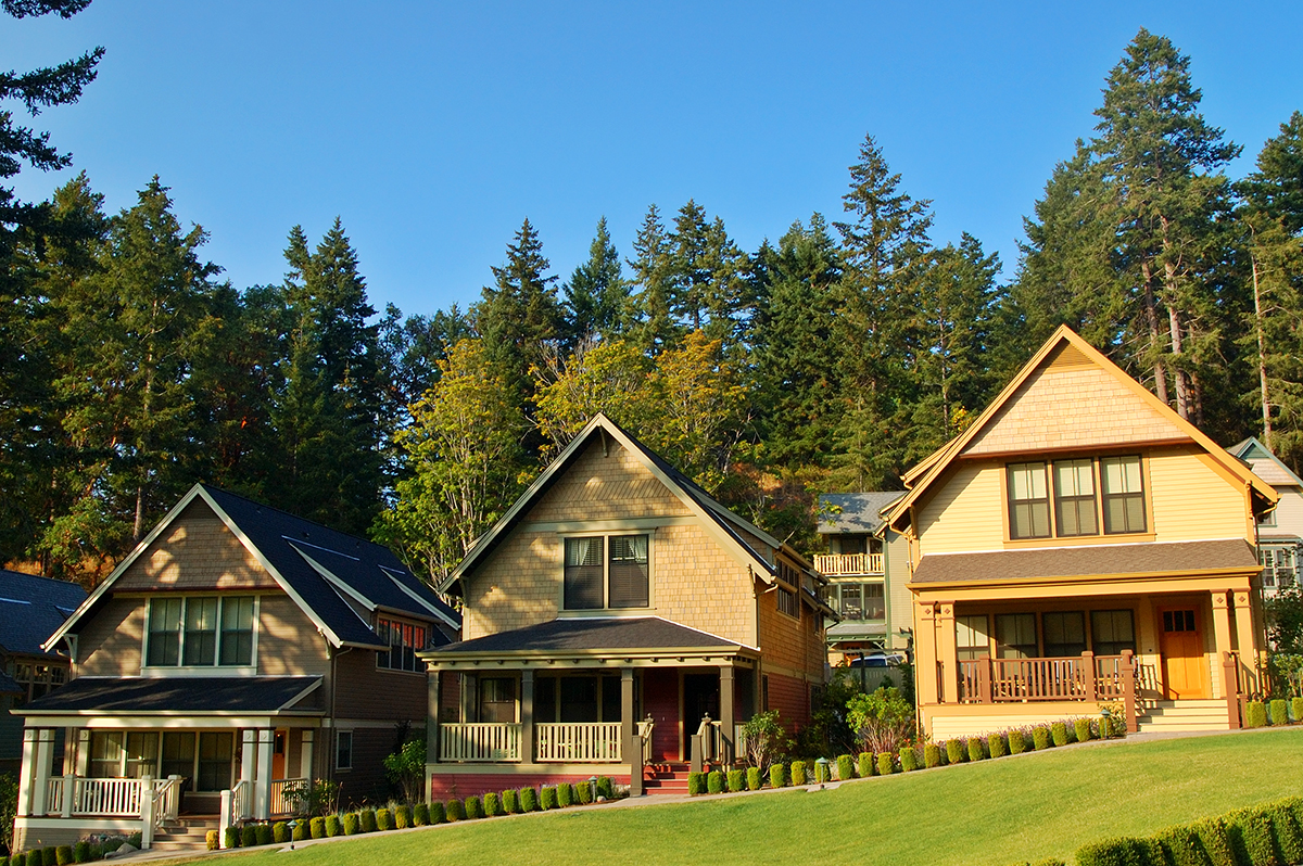 Row of three yellow houses with green grass in front and tall tress in back. home inspection